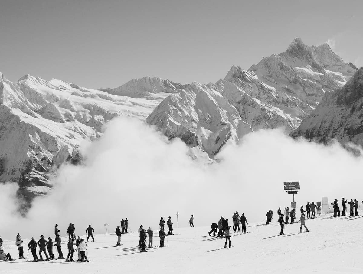 Skiers on a snowy slope with panoramic views of the Swiss Alps near Wengen