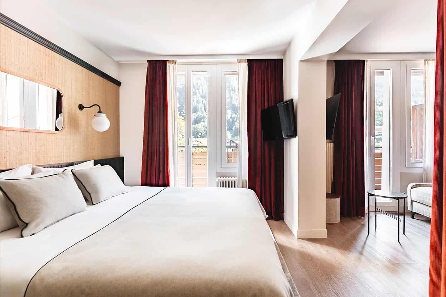 Spacious double room at Braunbär Hotel in Wengen with balcony access and mountain views.