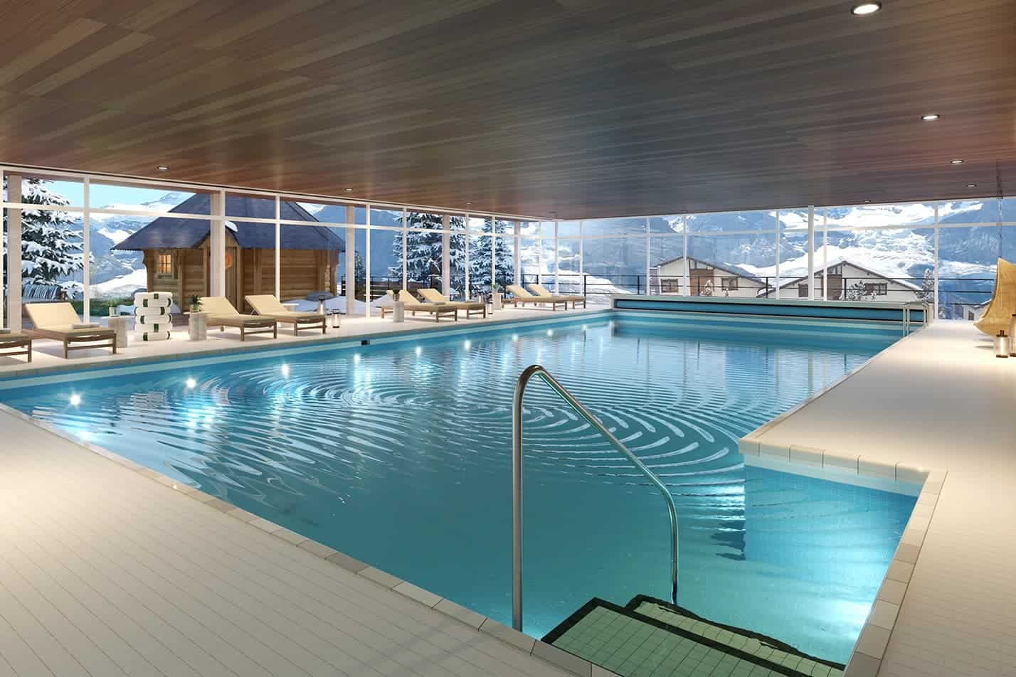Indoor swimming pool at Braunbär Hotel & Spa in Wengen with panoramic alpine views and lounge chairs.