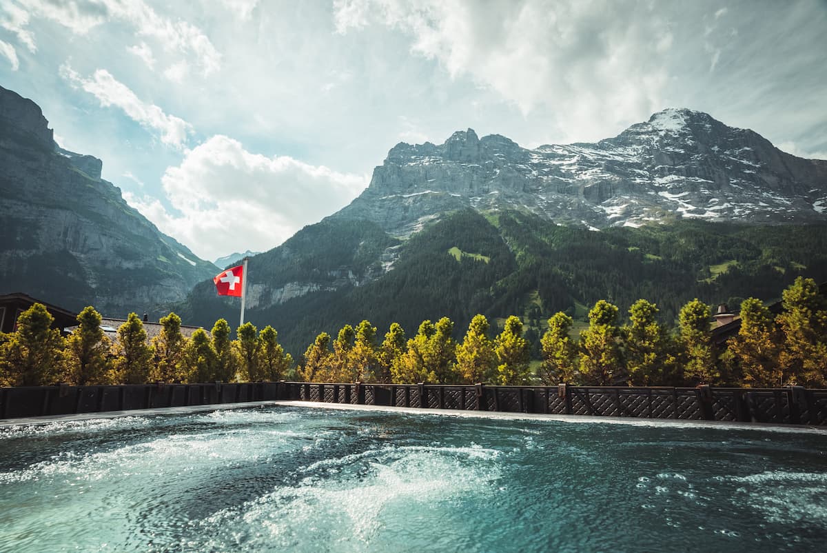 Outdoor spa pool at Hotel Glacier Grindelwald with Swiss flag, boutique hotel wellness and Eiger mountain views in Grindelwald, Switzerland